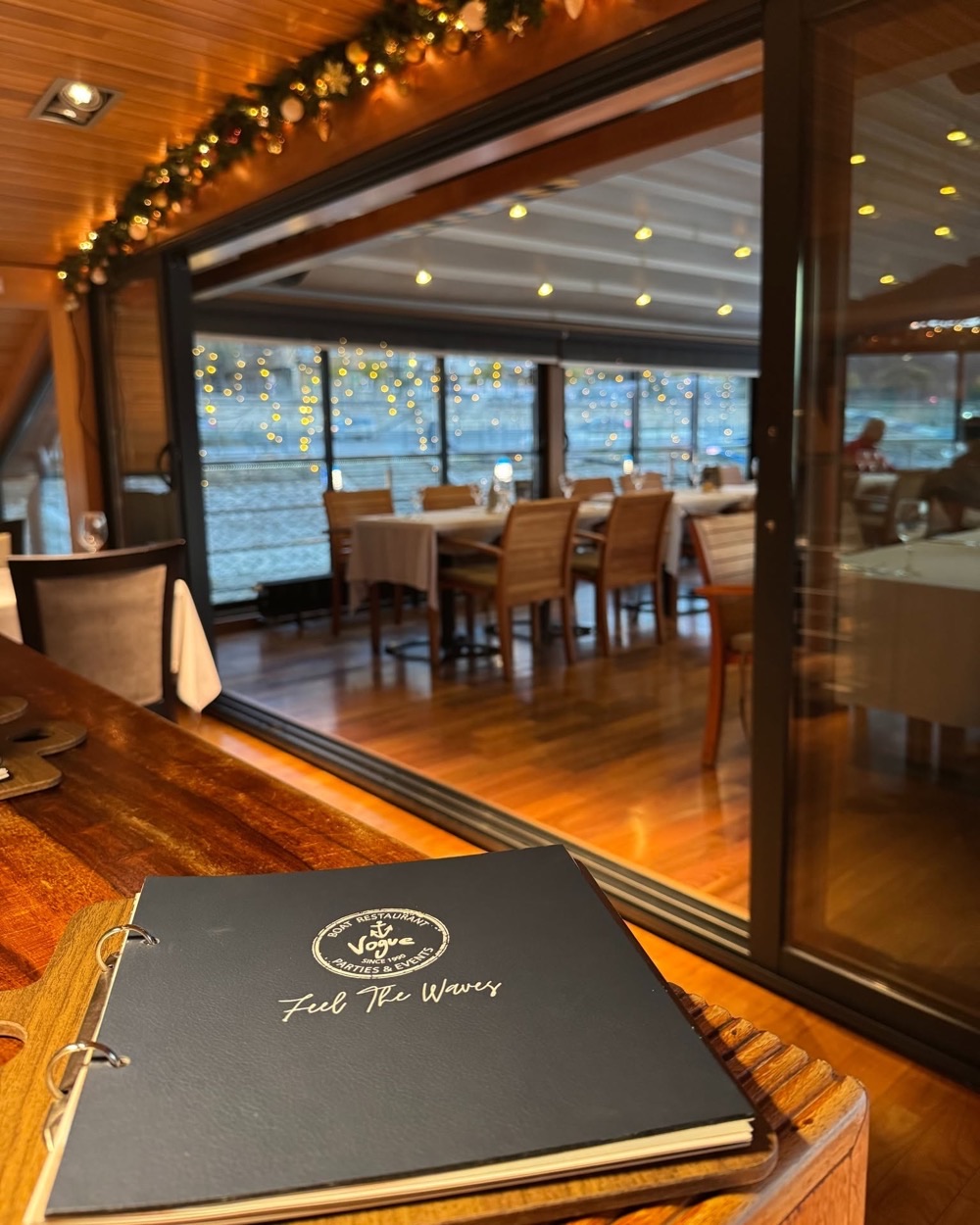 A menu card with the Vogue crest, the room behind it strung with Christmas lights